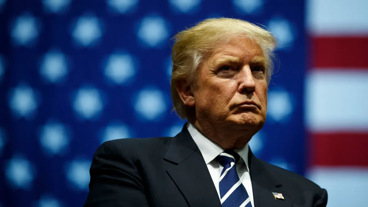 Former President Donald Trump sits in front of an American flag.