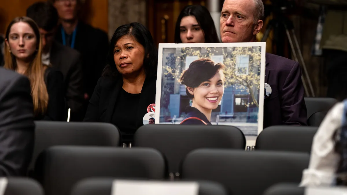 A man and woman hold a photo of their daughter.