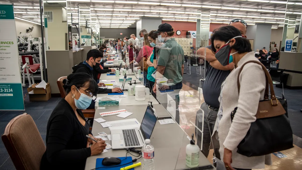 Patients wait to check-in at a line of kiosks to get vaccinated.