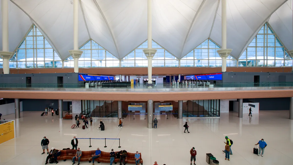 A crowd of people milling about in an airport lobby on the first and second levels.