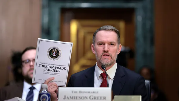 U.S. Trade Representative Jamieson Greer holds up a document that says "foreign trade barriers."