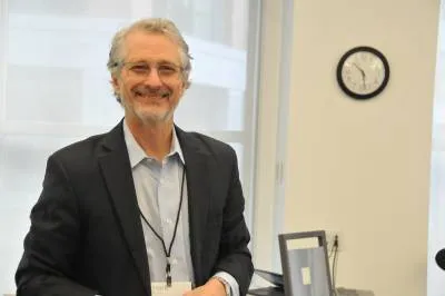 Person standing in a suit and glasses in an office