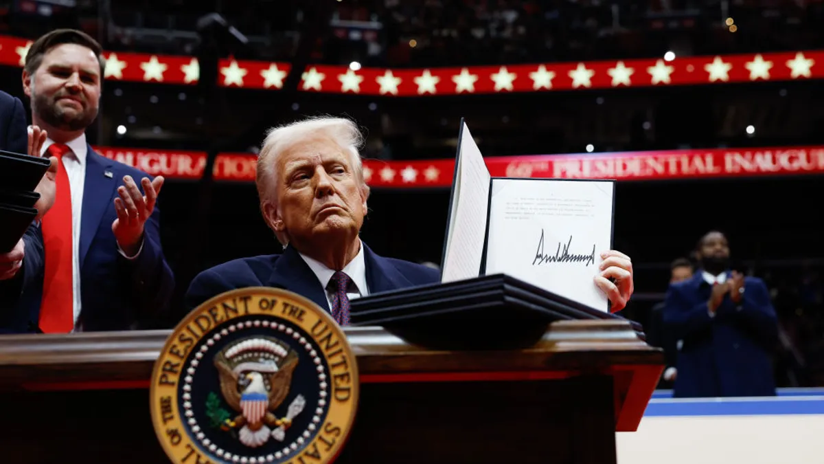 President Donald Trump holds up an executive order after signing it at Capital One Arena in Washington, D.C.