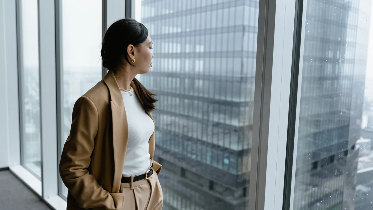 An Asian person looks out the window at an office