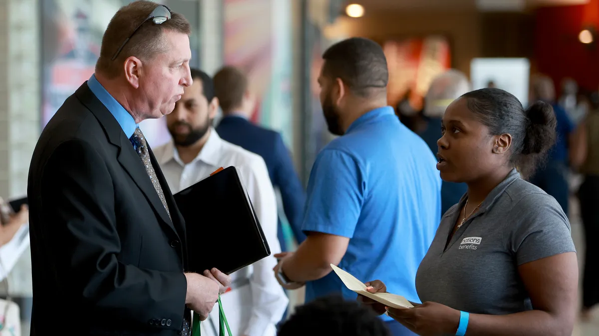 Two people talk at a job fair.