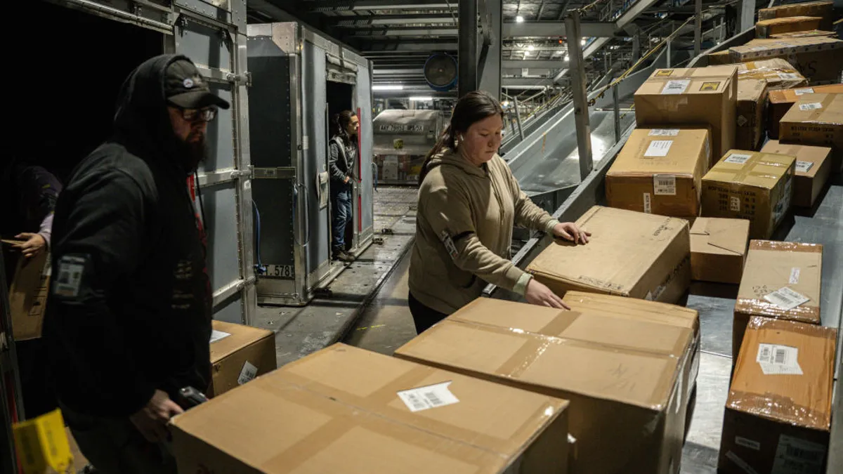 UPS employees load boxes from a posi-sorter chute into an air container at UPS Worldport on January 3, 2022 in Louisville, Kentucky.