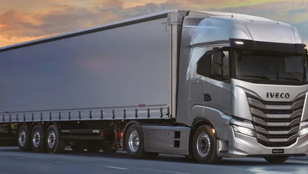 An IVECO tractor-trailer on a road with power lines in the background.