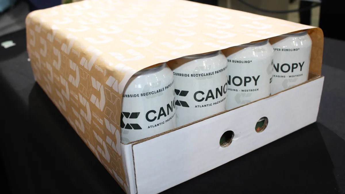 A 24-pack of beverage cans sitting in a cardboard base with a fiber wrapper around them.