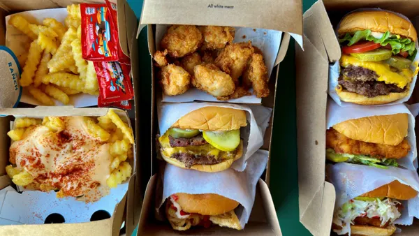A photograph of various burgers, chicken sandwich, chicken nuggets and fries in cardboard packaging.