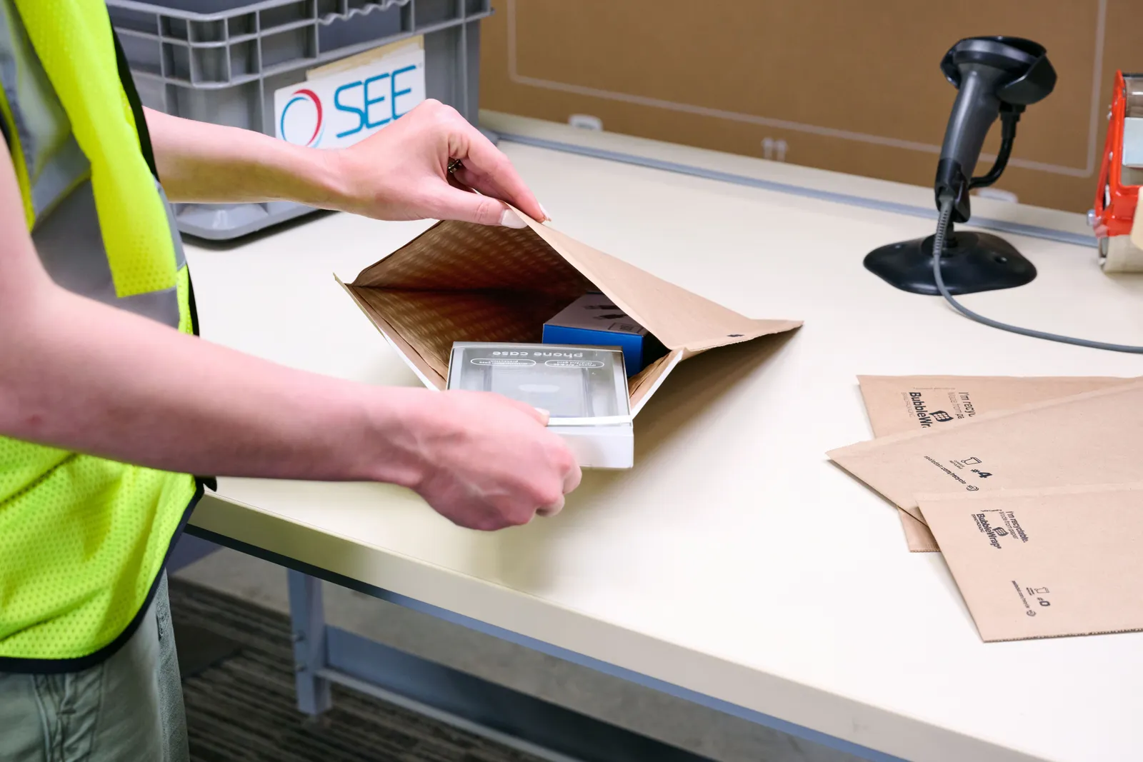 A person opens a fiber e-commerce mailer and places an item inside.