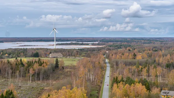 A wind turbine spins in an autumn landscape.