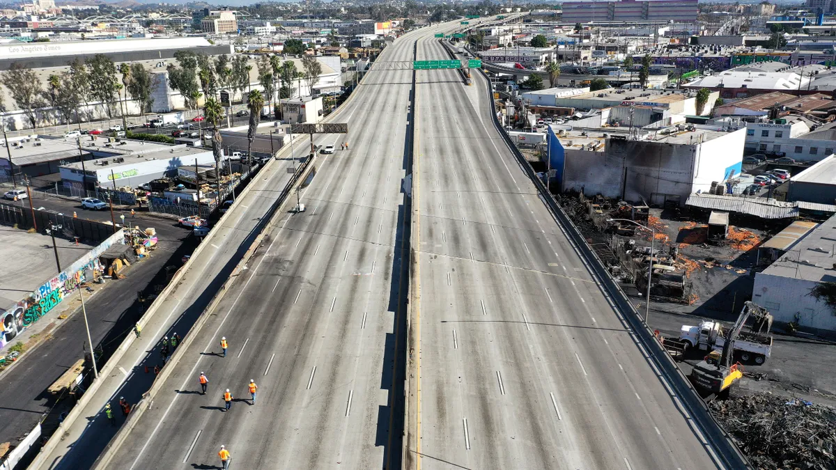 An aerial view shows workers walking on the closed I-10 freeway following a large pallet fire in Los Angeles.