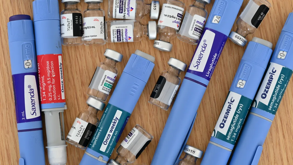 Drug injection pens and vials are arranged on a wooden table.