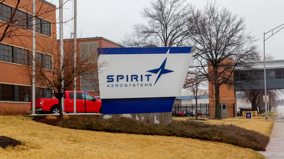 A blue and white Spirit AeroSystems sign in front of a red brick building.