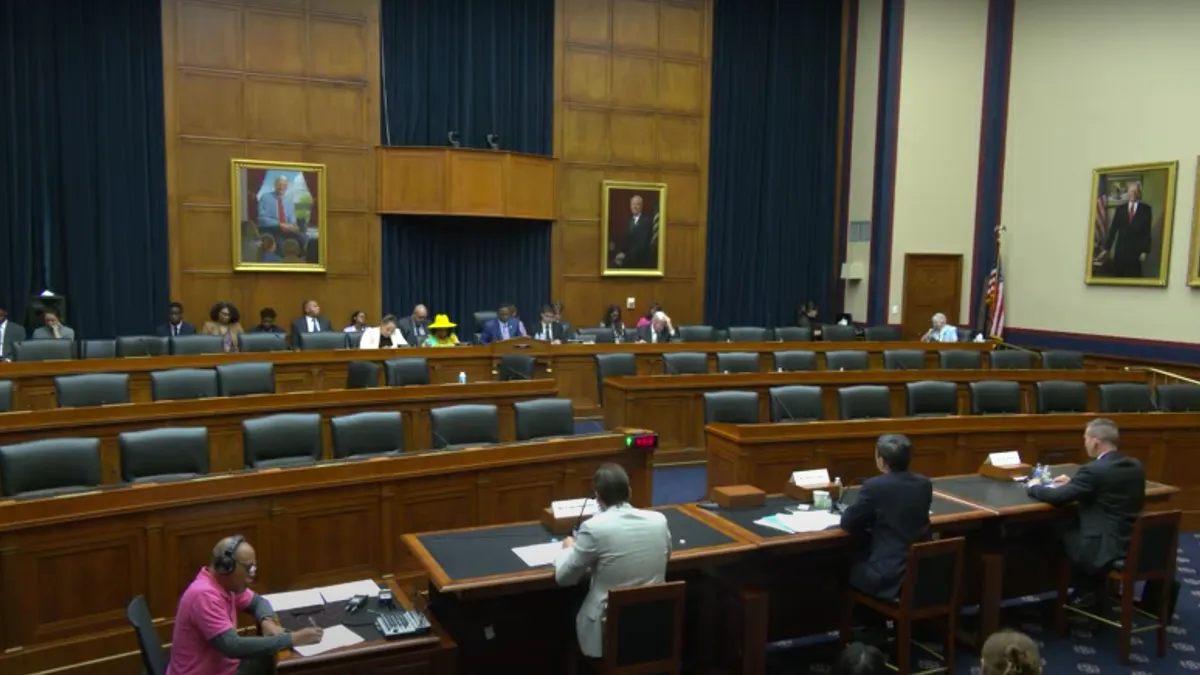 A wide-angle shot of a mostly-empty Congressional hearing room