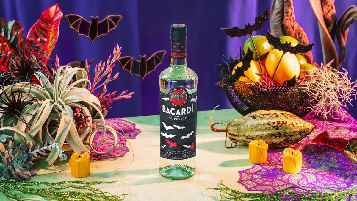 A Halloween themed Bacardi bottle on a table with Halloween decorations and bats.