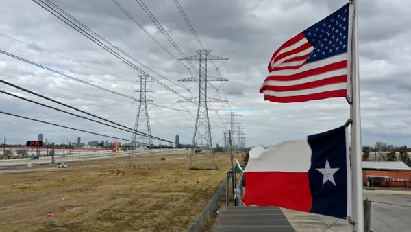 The U.S. and Texas flags fly in front of high voltage transmission towers.