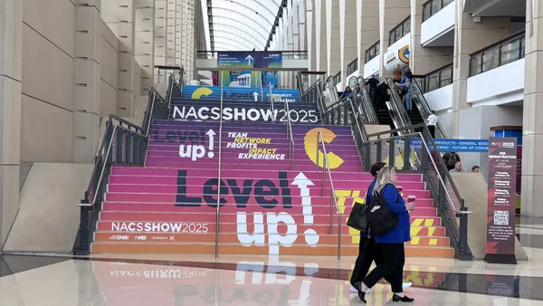 A photo of a set of stairs with signs on the front of each step. The signs read "Level Up! NACS Show 2025."