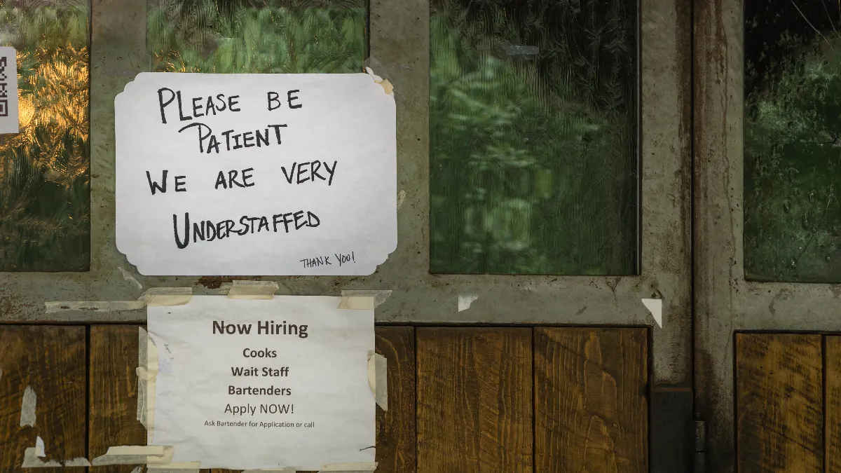 An image of two signs, one that says "Please be patient we are understaffed" and "Now hiring cooks, wait staff, bartenders. Apply now."