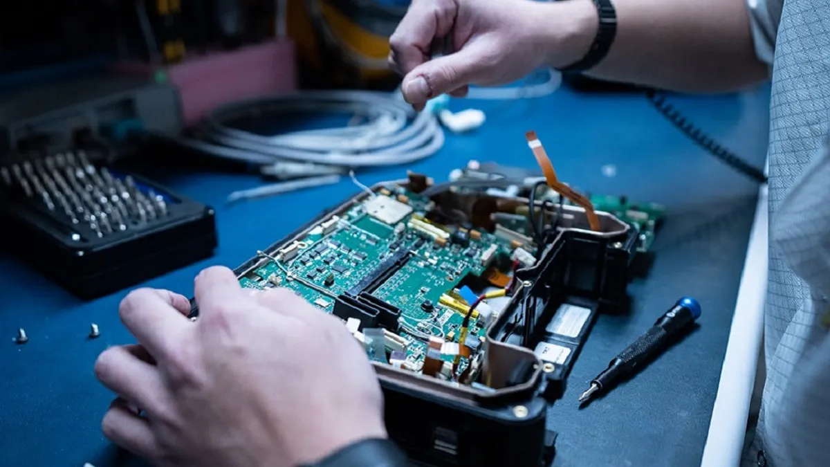 Medical device opened up on repair table with technician working