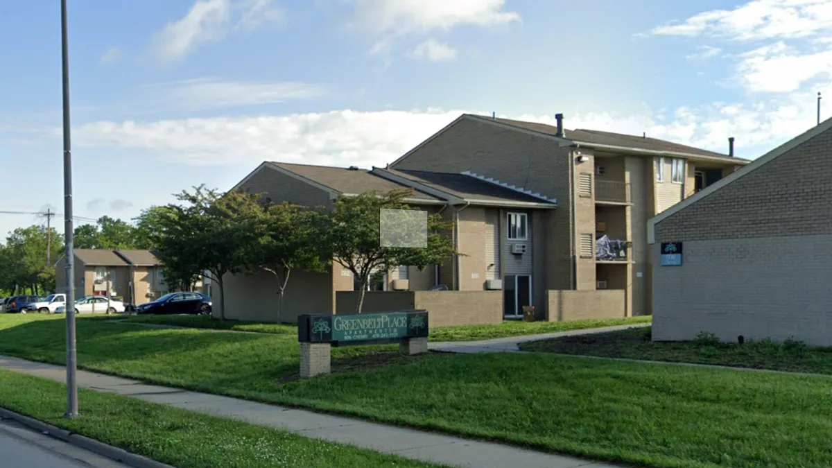 A low-rise apartment building. A sign in front reads "Greenbelt Place."