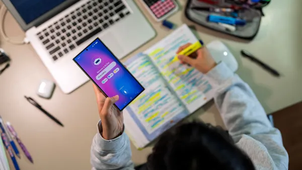 A student holds their phone while using a generative artificial intelligence app as they complete their homework.