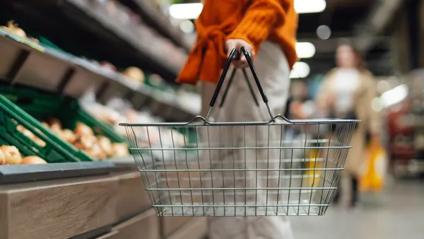 Cropper shot of young woman carrying a shopping basket while shopping in supermarket
