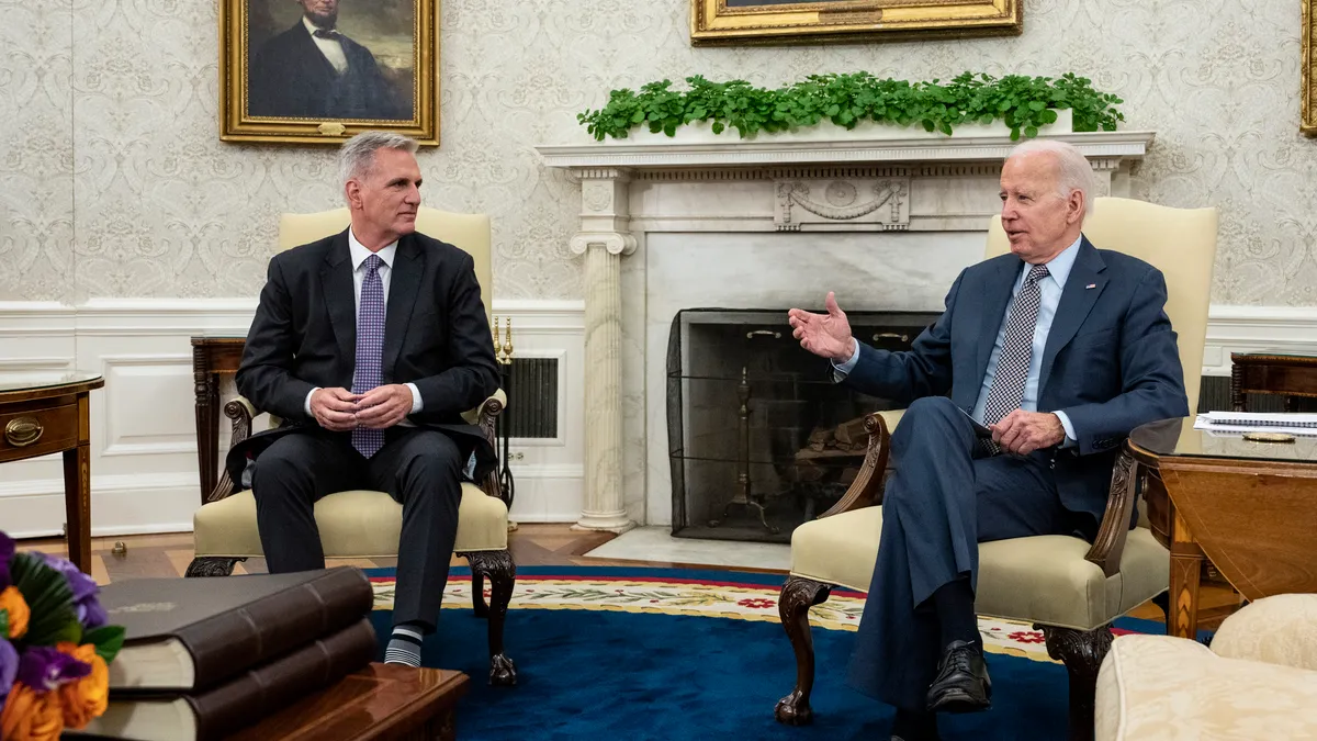 U.S. President Joe Biden and House Speaker Kevin McCarthy are seated in armchairs in the Oval Office.