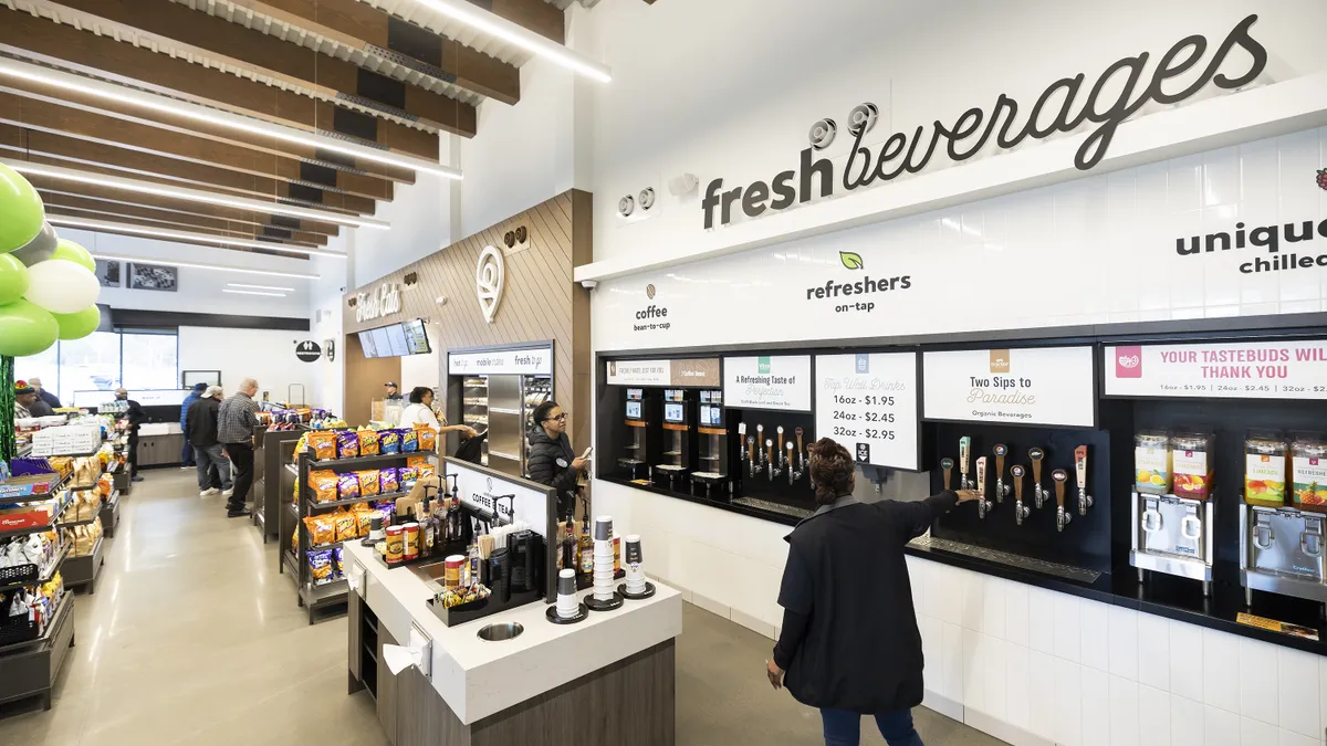 A photo of the inside of a convenience store, showing taps for dispensed beverages, a counter for ordering fresh food and shelves of products.  A sign on the wall says fresh beverages.