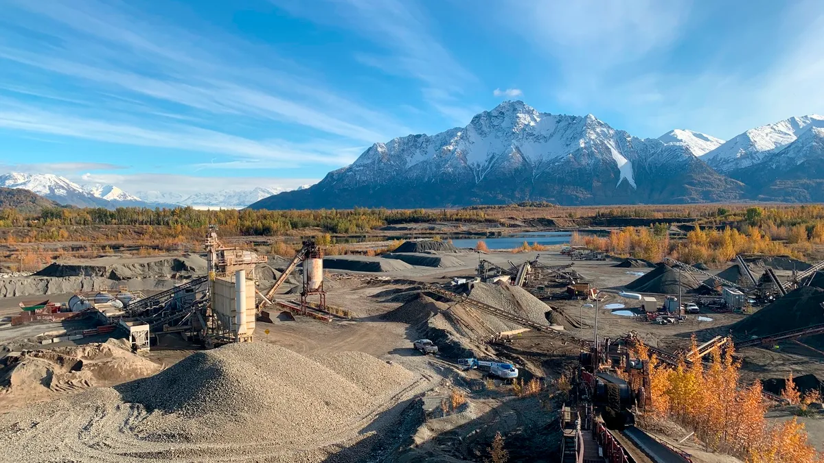 An aggregate facility stands in the foreground of dramatic mountains in Alaska.