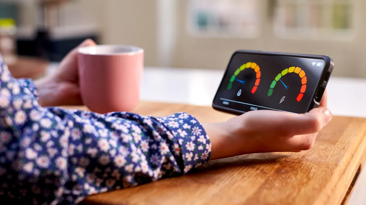 Close Up Of Woman Holding Smart Energy Meter In Kitchen Measuring Domestic Electricity And Gas Use