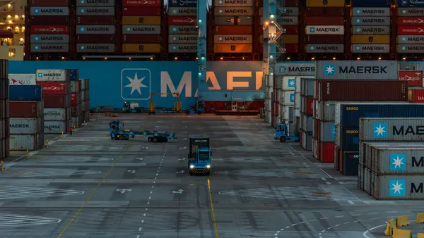 A  view of containers stacked on a port terminal and a shipped docked in the background.
