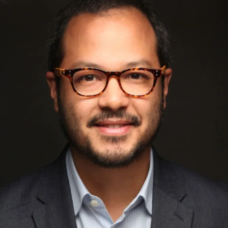 A man with glasses looks into the camera for a closeup.