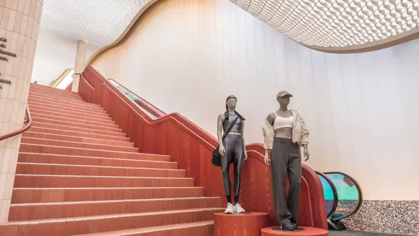 Two mannequins at the foot of a red set of stairs in Lululemon's SoHo store.