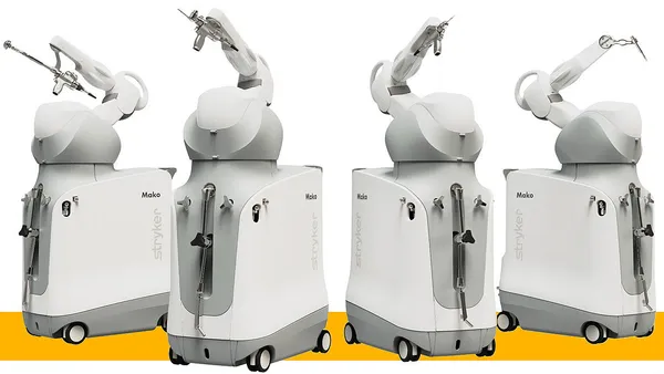 Four robots side by side with a single arm have different instruments attached to the end.