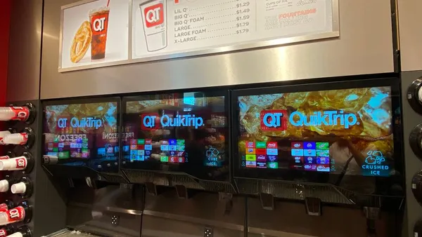 A photo of a bank of dispensed beverage machines with touch screens. The screens say QR QuikTrip. The menu above the machines says "Fountain."