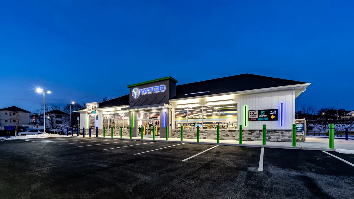 A photo of the exterior of a store, seen at night with all its lights on. A sign over the door says Yatco.