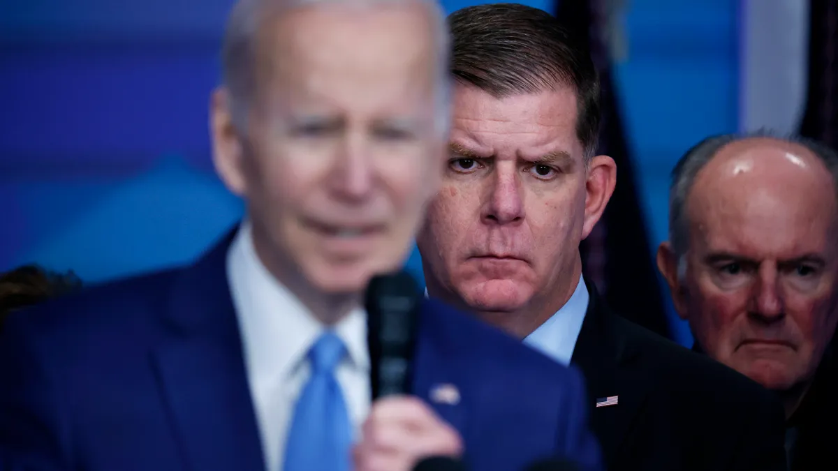 Marty Walsh stands behind President Joe Biden as he delivers a speech.