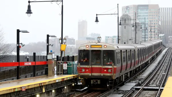 A Boston elevated train pulls into a station on a cloudy day.