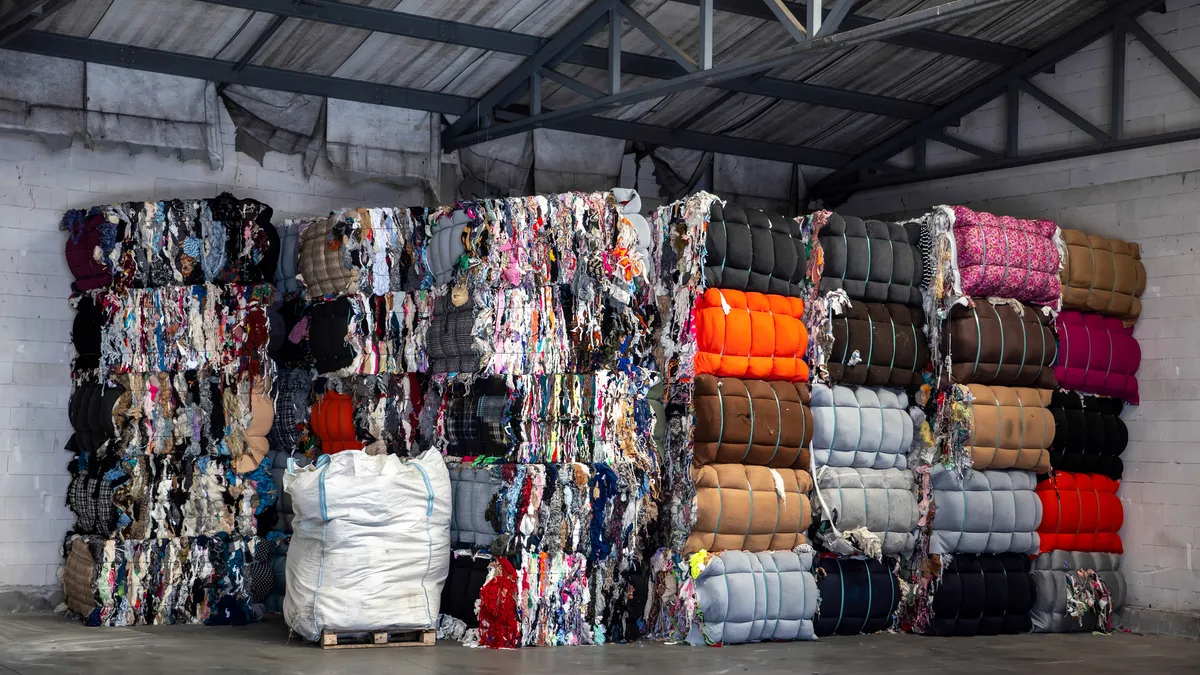 Bales of clothing and textiles are pictured in a store house.