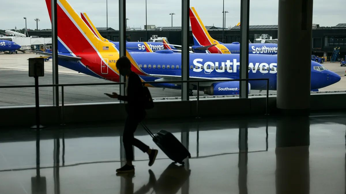 A traveler walks past a Southwest Airlines airplane as it taxies from a gate at Baltimore Washington International Thurgood Marshall Airport on October 11, 2021 in Baltimore, Maryland.