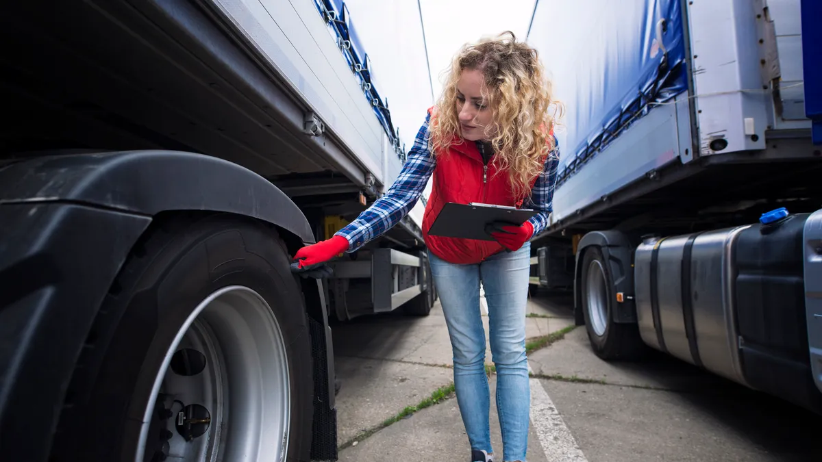 A worker inspects a truck tire.