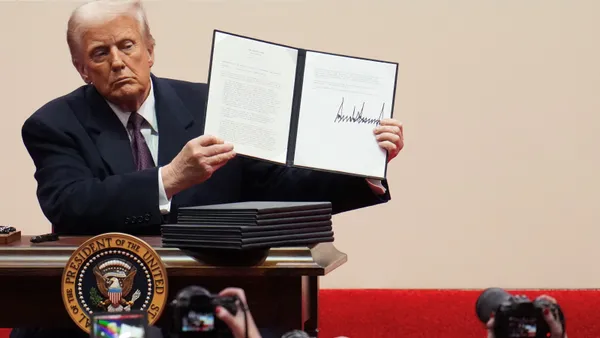 President Donald Trump holds up a signed executive order