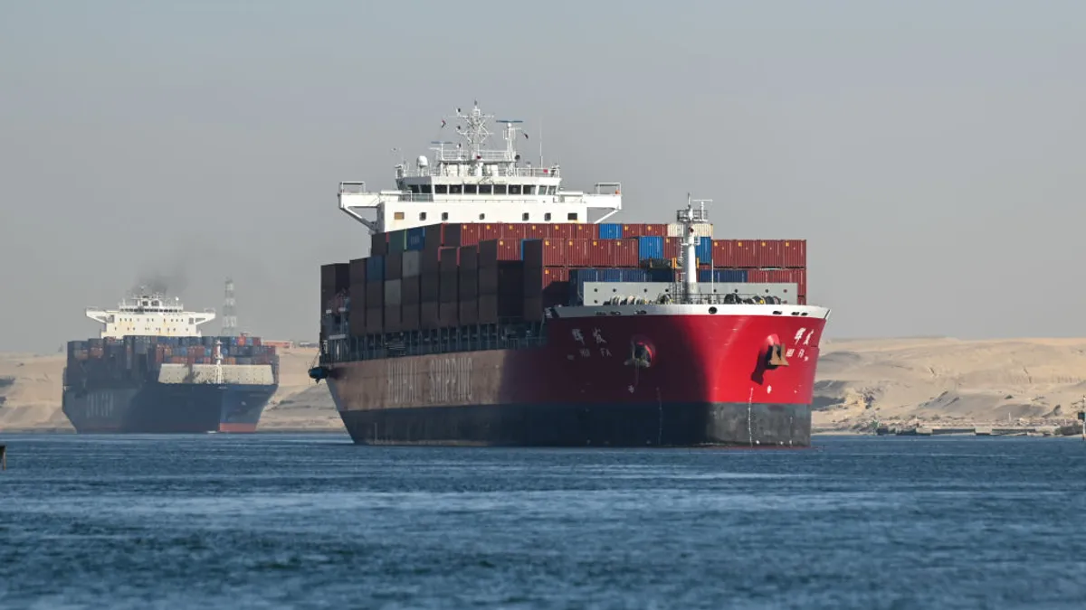 Two cargo ships transit on water through the Suez Canal