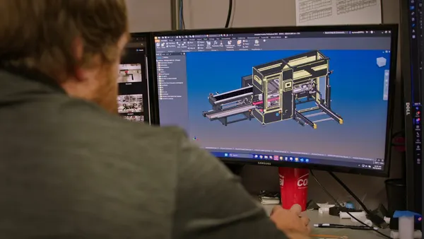 Employee on a desktop computer looking at a diagram of a piece of machinery