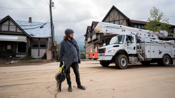 A person surveys storm damage in front of a utility truck.