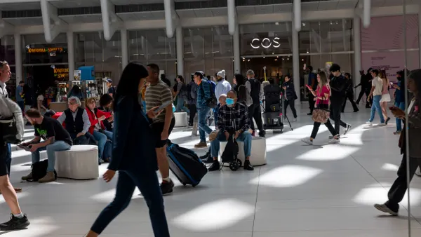 Many people walk through a transportation and shopping hub.