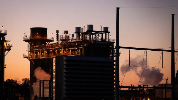 A gas plant is seen against a sunset sky.