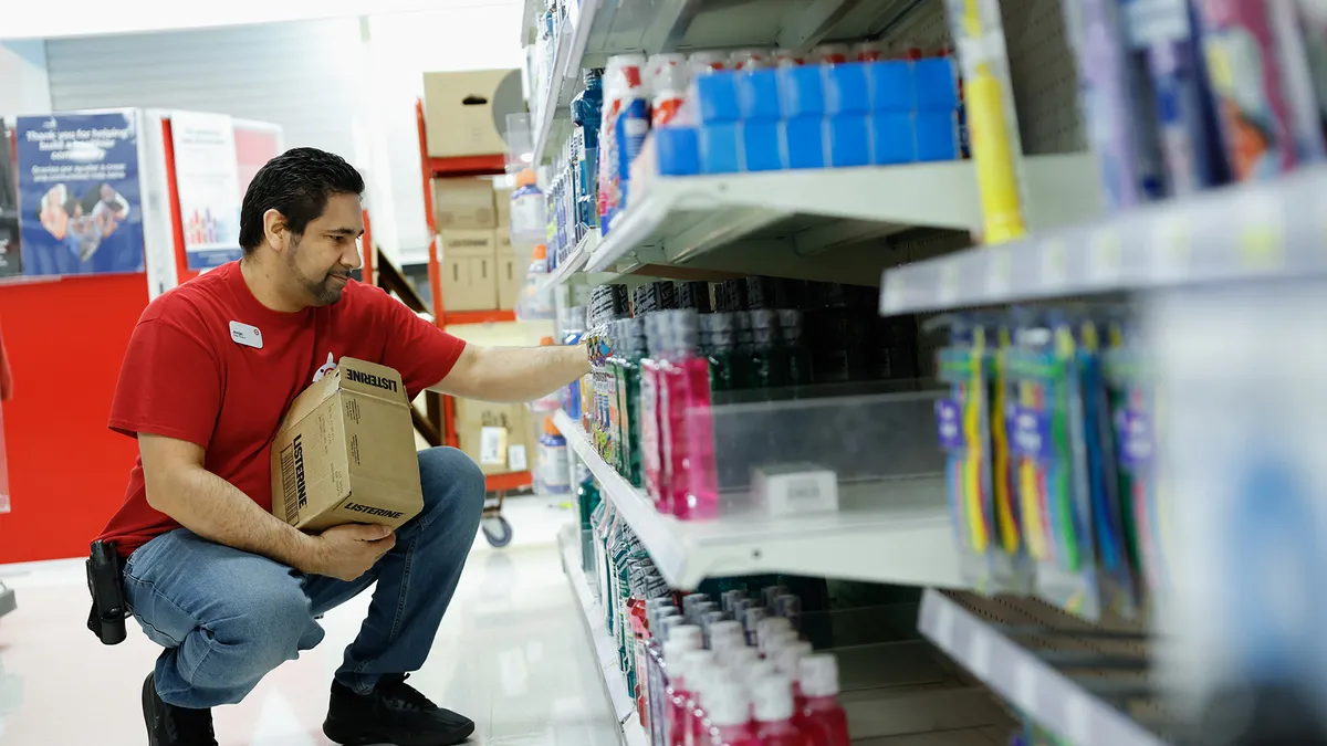 A store employee wearing a red Target vest puts health and beauty products on a store shelf.