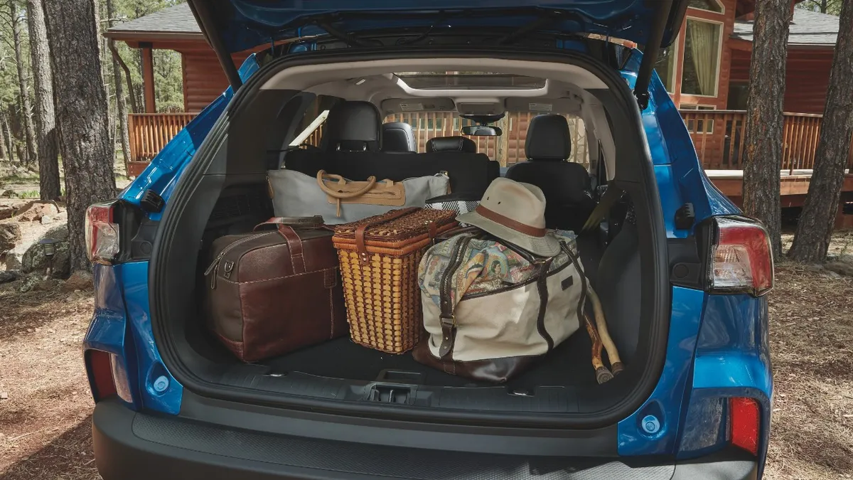 The back of a 2021 Ford Escape with the rear liftgate open and luggage and other items inside.